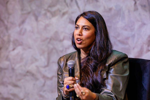 Nabiha holds mic while speaking seated on stage