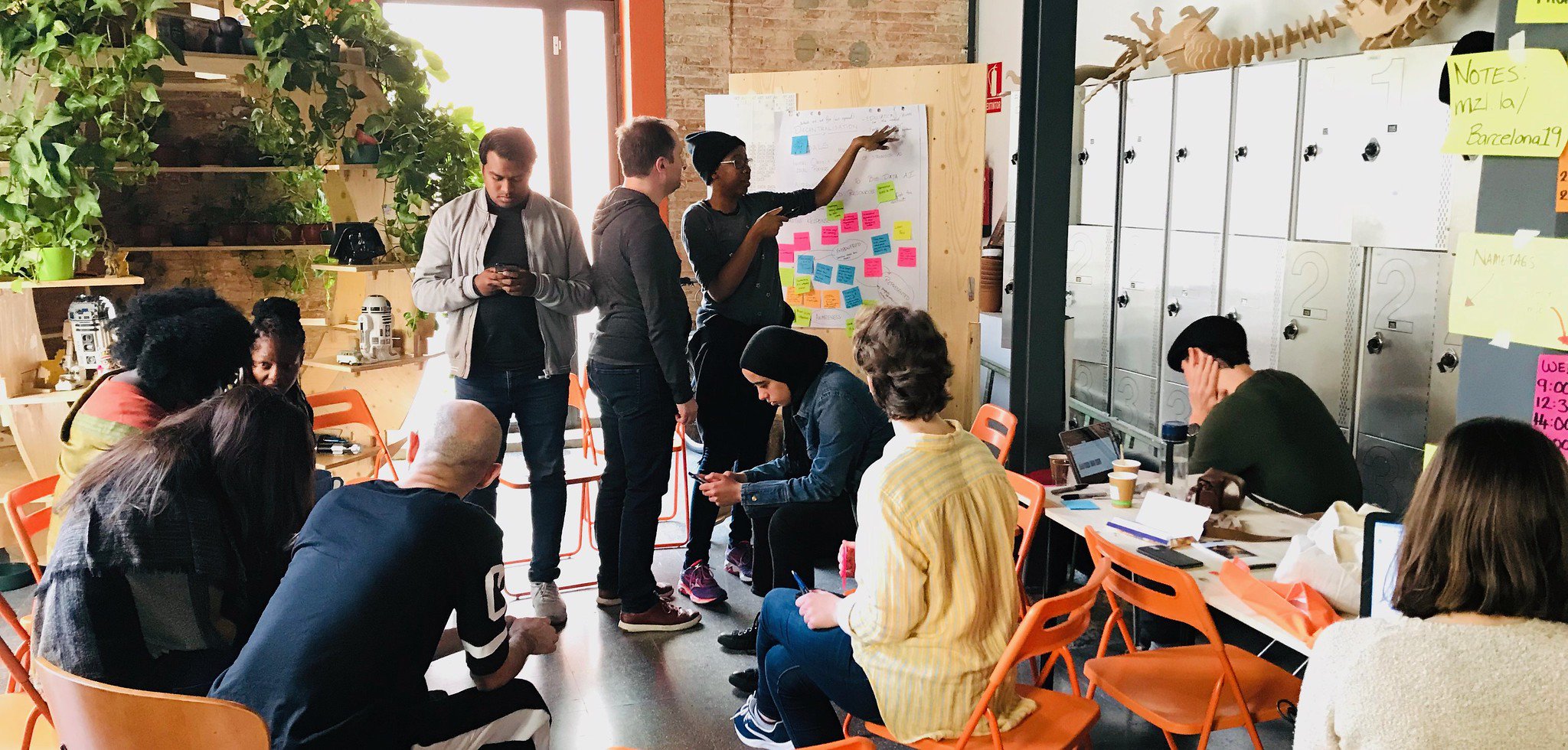 A group of MozFest Wranglers, discussing ideas and using sticky notes to mind map on a board.