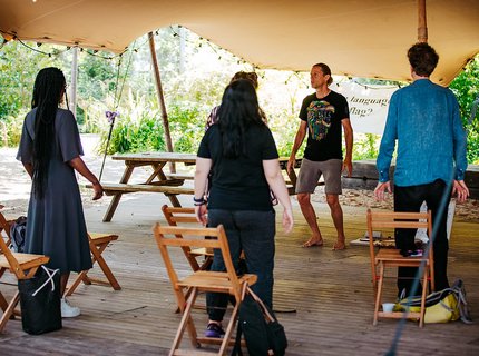 A group of people facing an instruction taking part in a yoga class