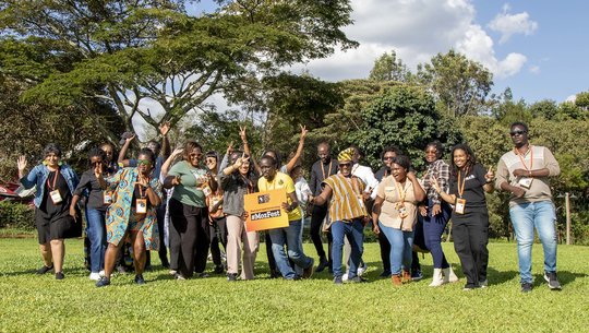 A group of Wranglers, cheering and celebrating outside on grass at MozFest House Kenya.