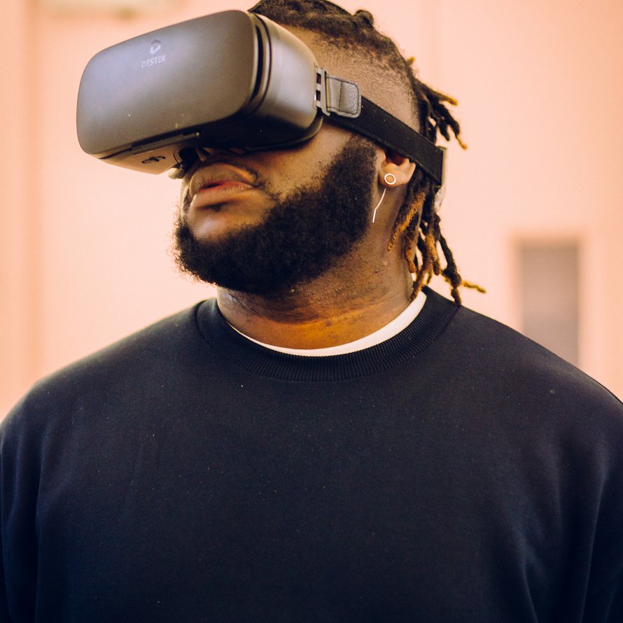 A person with a black beard wearing a VR headset and black sweater.