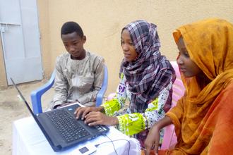 Chamsa Al Marif Nime, a Digital Grassroots Ambassador from Chad, sits with two other young people while they use a computer connected to a mobile internet modem.jpg