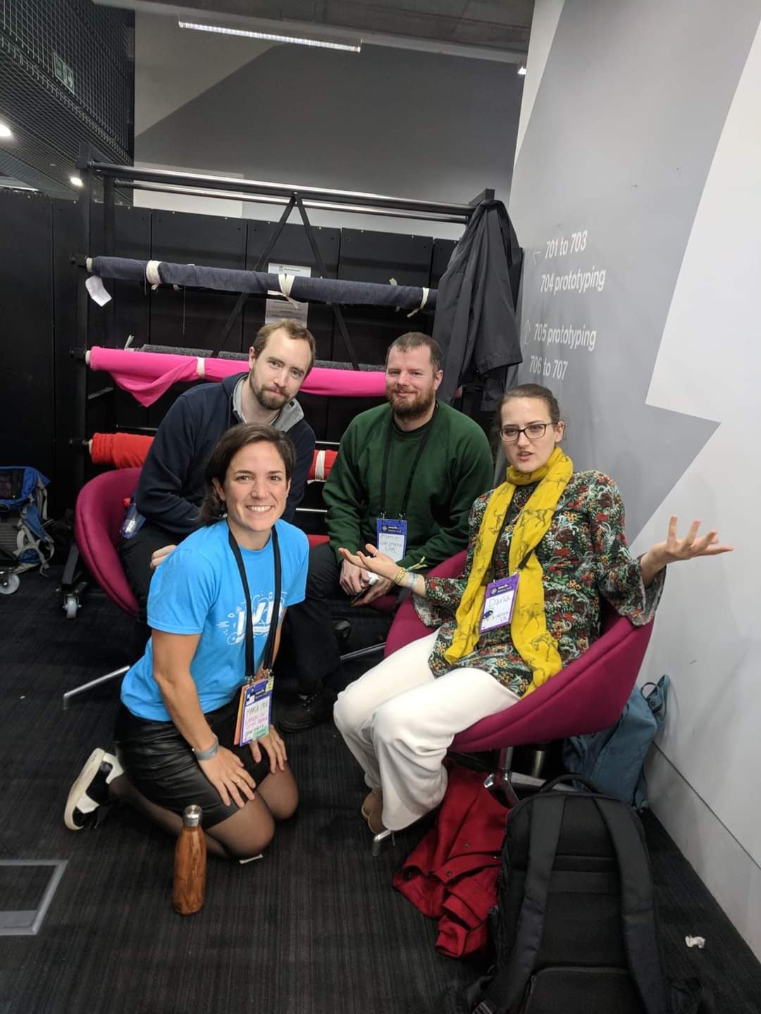 group of four people smiling at the camera sitting in chairs in a building