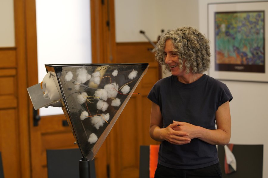 A woman smiles while viewing an intriguing piece of art