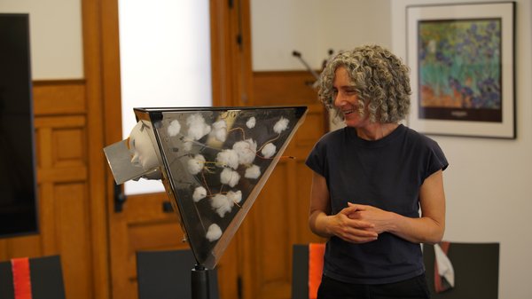A woman smiles while viewing an intriguing piece of art