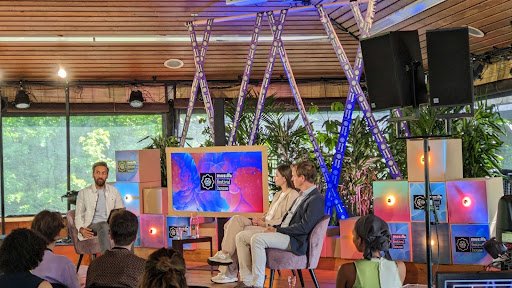 A group of people sitting on a colorful stage, chatting.