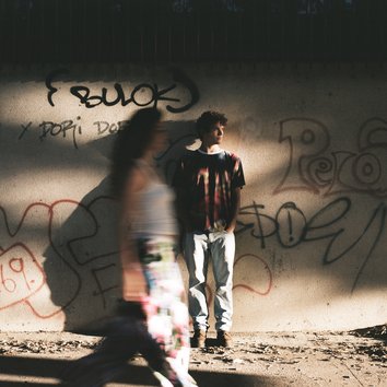 People wearing anti surveillance fashion in front of graffiti wall 