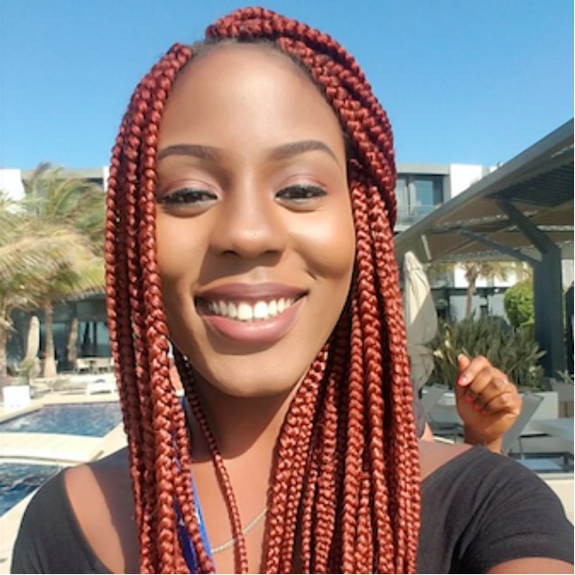 headshot of person with red, long hair and dark skin smiling at the camera