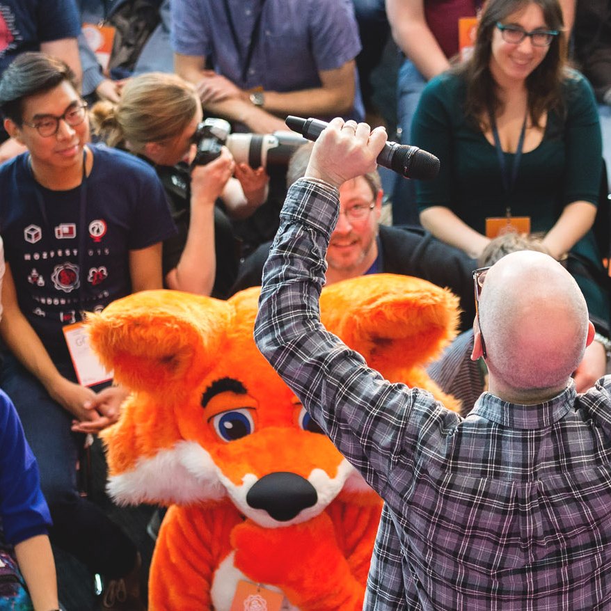 Una foto de una multitud de participantes en un evento previo del MozFest, enfocado en la mascota de Mozilla