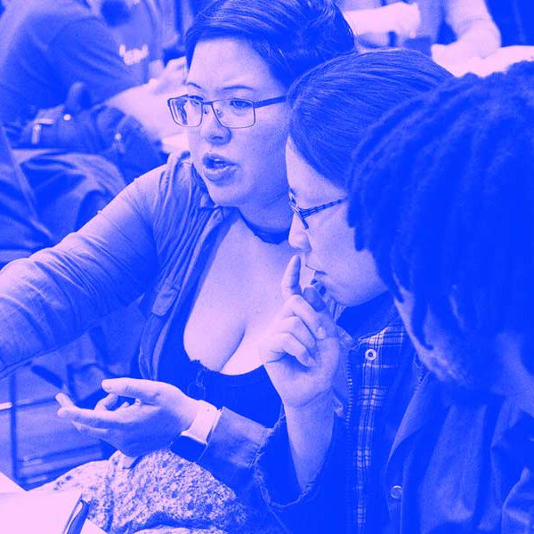 Three people sit around a laptop during a session a MozFest