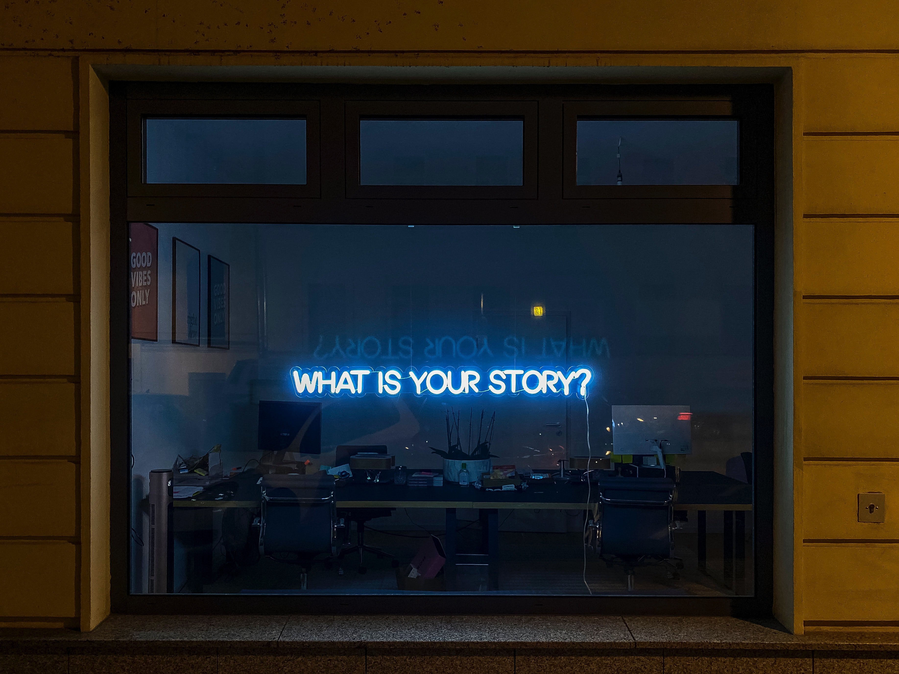 una ventana oscura con un letrero de neón que dice "¿Cuál es tu historia?"